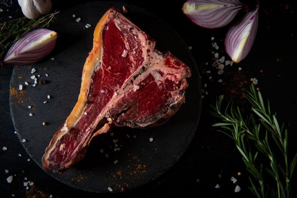 T-bone de bœuf d'aurochs vieilli, servi sur une assiette en ardoise et accompagné de légumes